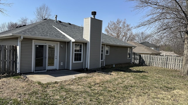 rear view of house featuring fence, roof with shingles, a lawn, a chimney, and a patio area