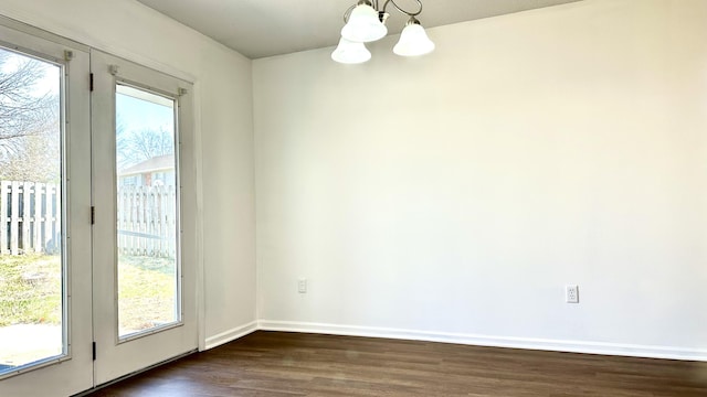 unfurnished room with baseboards, dark wood-type flooring, and a chandelier