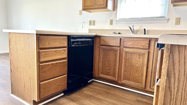 kitchen with dark wood-type flooring, light countertops, black dishwasher, brown cabinets, and a sink