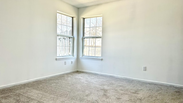 carpeted spare room with baseboards, a textured ceiling, and a healthy amount of sunlight