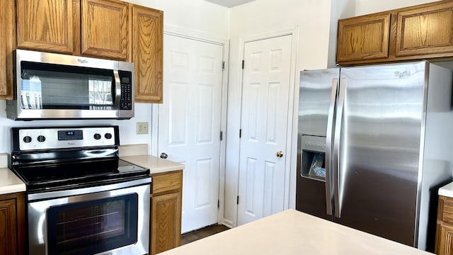 kitchen with light countertops, brown cabinets, and appliances with stainless steel finishes