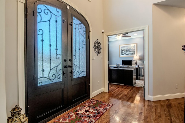 foyer with wood finished floors, french doors, baseboards, and arched walkways