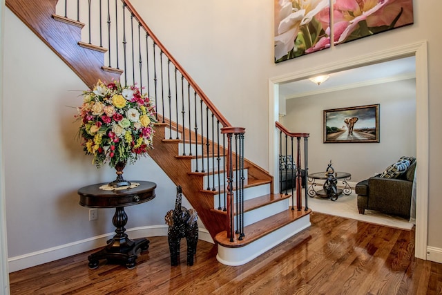 staircase with baseboards, wood finished floors, and crown molding