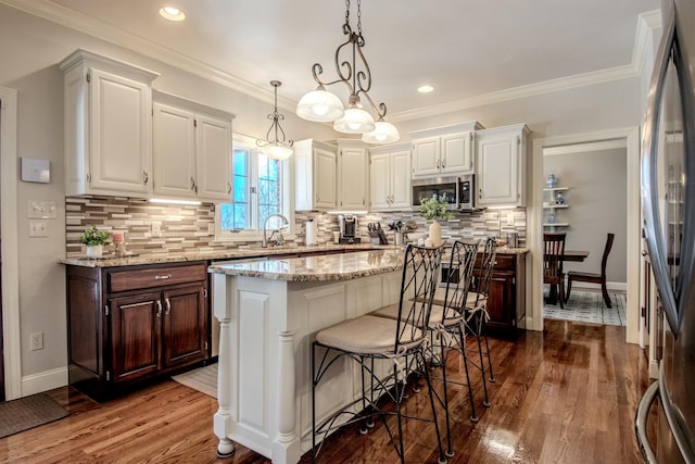 kitchen featuring stainless steel appliances, a kitchen island, dark wood finished floors, and ornamental molding