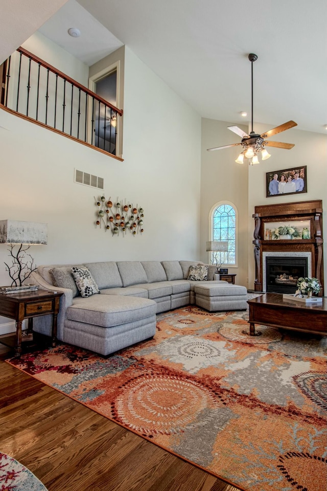 living area with visible vents, high vaulted ceiling, a ceiling fan, wood finished floors, and a fireplace