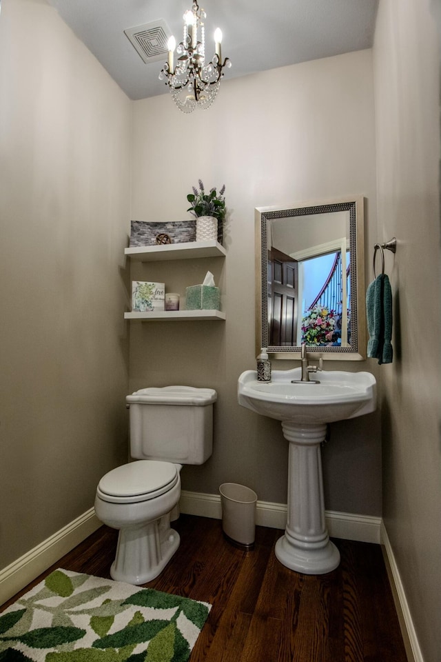 half bathroom with visible vents, toilet, a notable chandelier, wood finished floors, and baseboards