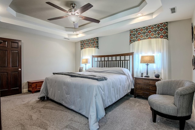 bedroom featuring visible vents, a ceiling fan, carpet, and a tray ceiling