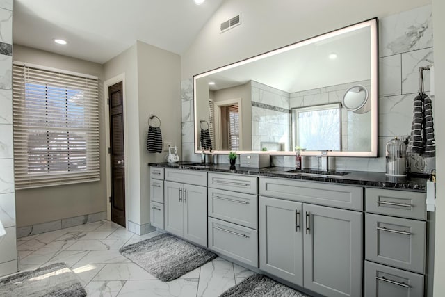 bathroom featuring visible vents, lofted ceiling, double vanity, marble finish floor, and a sink