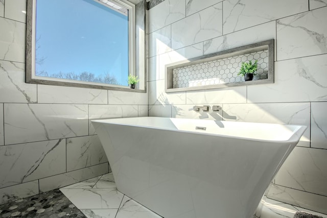 bathroom featuring marble finish floor and a freestanding bath