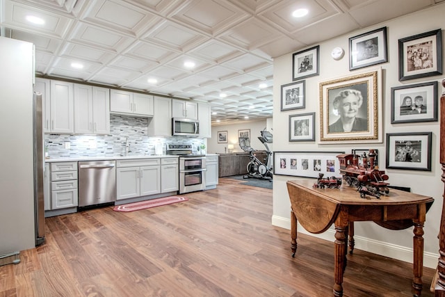 kitchen featuring tasteful backsplash, baseboards, light wood-style flooring, appliances with stainless steel finishes, and an ornate ceiling