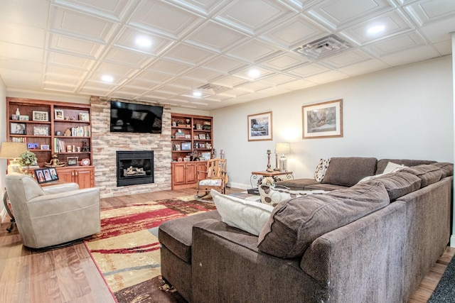 living area featuring built in shelves, an ornate ceiling, wood finished floors, a large fireplace, and baseboards