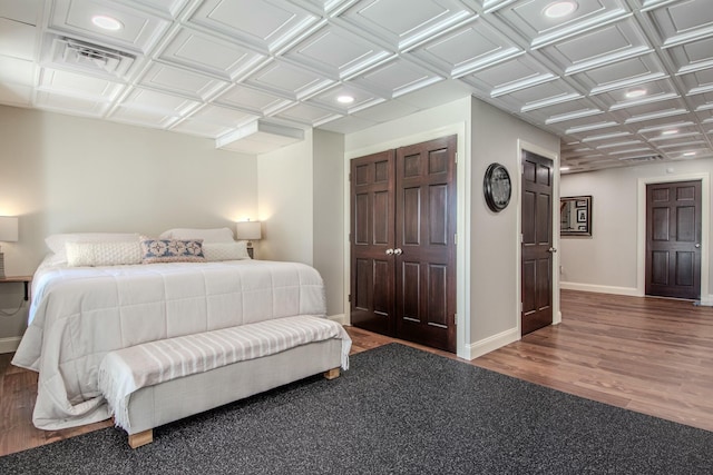 bedroom featuring visible vents, wood finished floors, baseboards, and an ornate ceiling