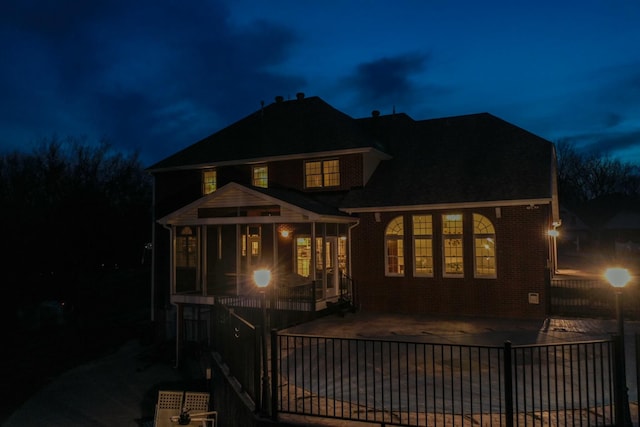 view of front of property with fence, brick siding, and a patio area