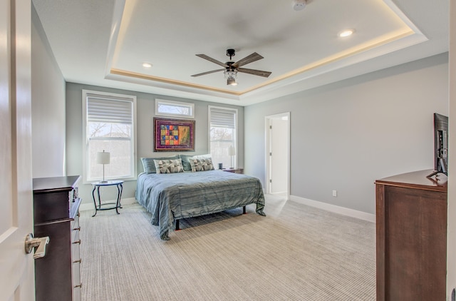 bedroom with a raised ceiling, a ceiling fan, baseboards, and light carpet