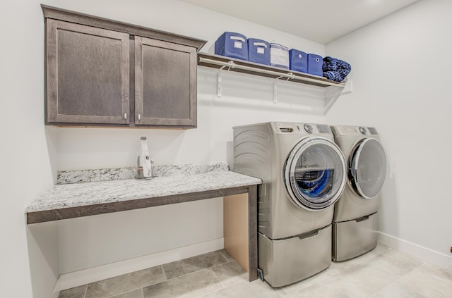 laundry room featuring baseboards, cabinet space, and washing machine and dryer