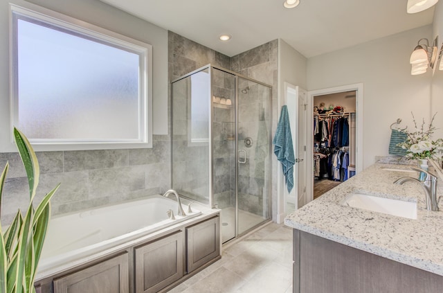 full bathroom with a garden tub, a sink, a shower stall, double vanity, and a spacious closet