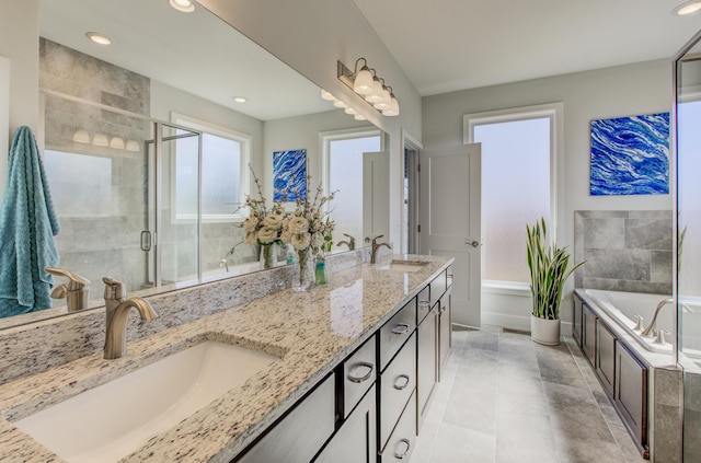 full bathroom with double vanity, a bath, a stall shower, and a sink