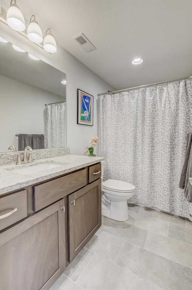 full bathroom featuring visible vents, toilet, vanity, and a textured ceiling