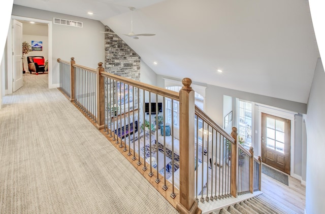 hall with an upstairs landing, visible vents, high vaulted ceiling, and baseboards