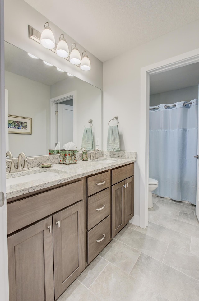 bathroom with double vanity, toilet, and a sink