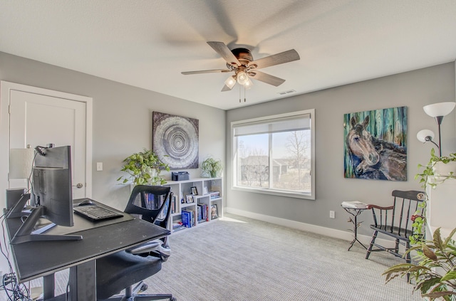 carpeted office with visible vents, baseboards, and a ceiling fan