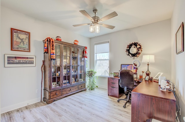 home office featuring light wood finished floors, a ceiling fan, and baseboards