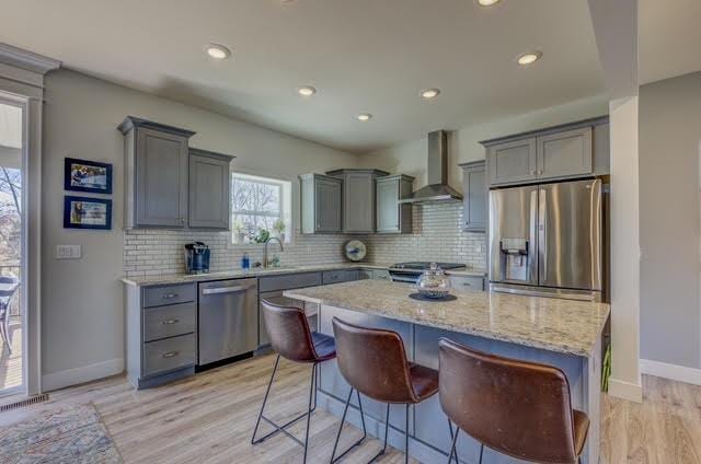 kitchen featuring gray cabinetry, stainless steel appliances, and wall chimney exhaust hood