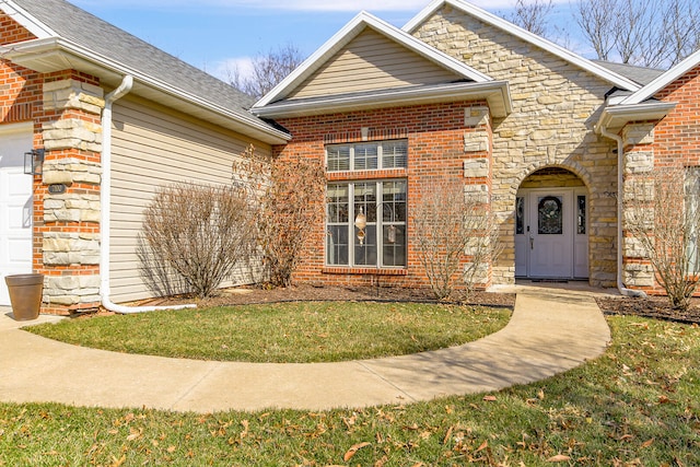 doorway to property featuring brick siding, stone siding, a lawn, and an attached garage