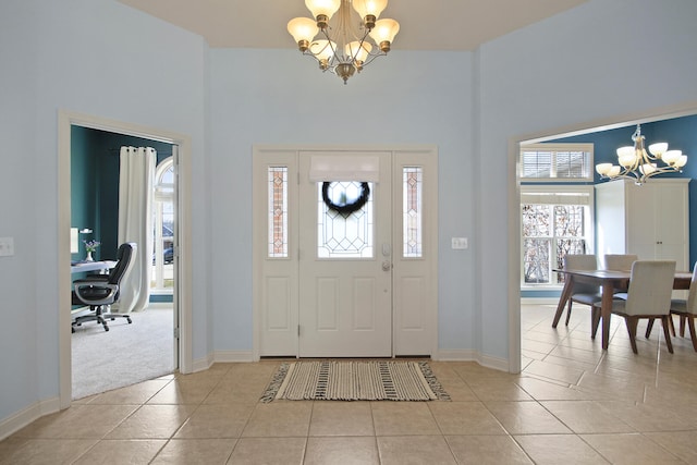 entryway with a high ceiling, light tile patterned floors, baseboards, and a chandelier