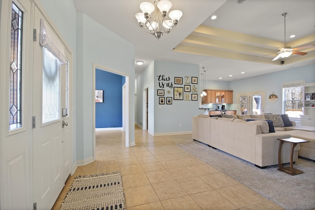 living room with light tile patterned floors, baseboards, recessed lighting, a raised ceiling, and ceiling fan with notable chandelier