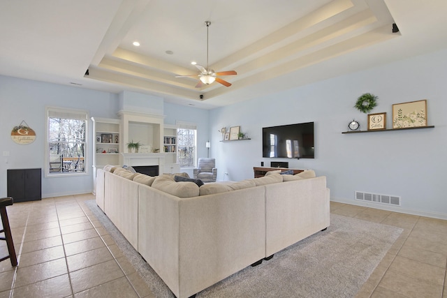 living room with visible vents, baseboards, a fireplace, light tile patterned flooring, and a raised ceiling