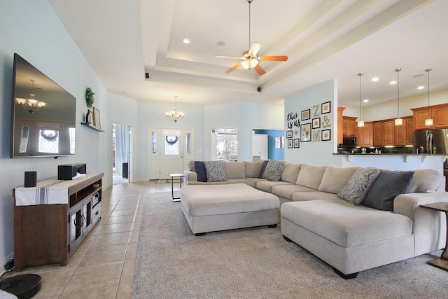 living room with light tile patterned floors, recessed lighting, ceiling fan with notable chandelier, and a tray ceiling