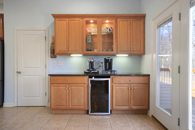 kitchen with dark stone countertops, wine cooler, brown cabinetry, and glass insert cabinets