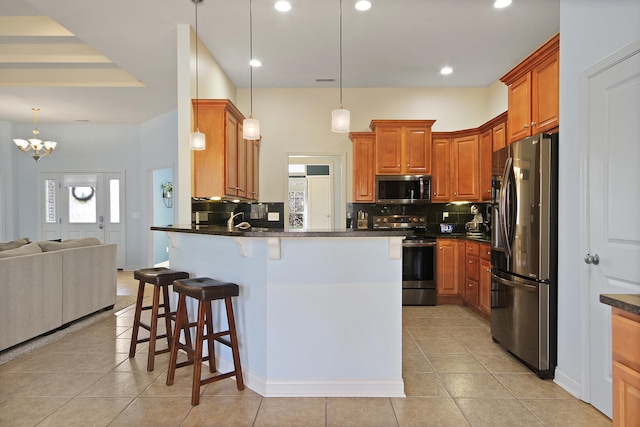 kitchen with a peninsula, stainless steel appliances, a kitchen bar, dark countertops, and open floor plan