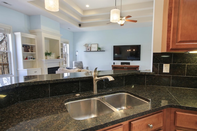 kitchen featuring visible vents, a sink, tasteful backsplash, open floor plan, and a fireplace