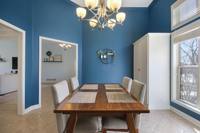 dining space featuring light tile patterned floors, baseboards, visible vents, a towering ceiling, and a notable chandelier