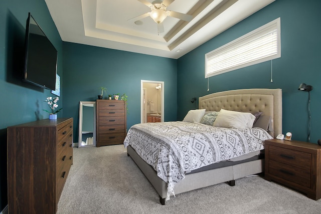 bedroom featuring a tray ceiling, ensuite bathroom, carpet floors, and ceiling fan