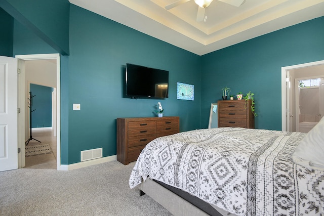 carpeted bedroom featuring visible vents, a raised ceiling, and baseboards