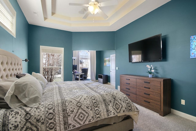 bedroom with carpet, baseboards, ceiling fan, a towering ceiling, and a raised ceiling