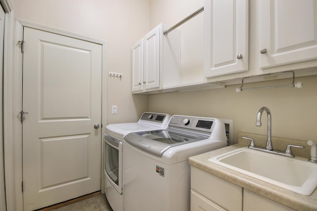 laundry area with washing machine and clothes dryer, cabinet space, and a sink