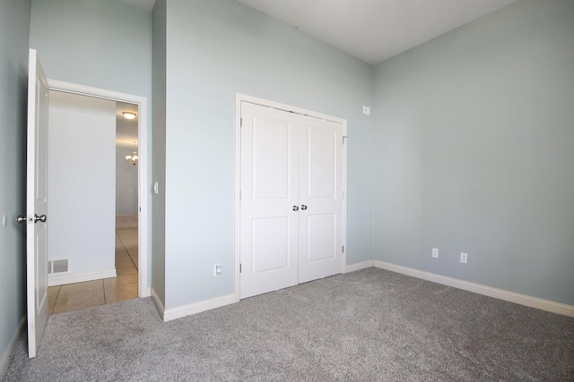 unfurnished bedroom with tile patterned flooring, visible vents, baseboards, carpet flooring, and a closet