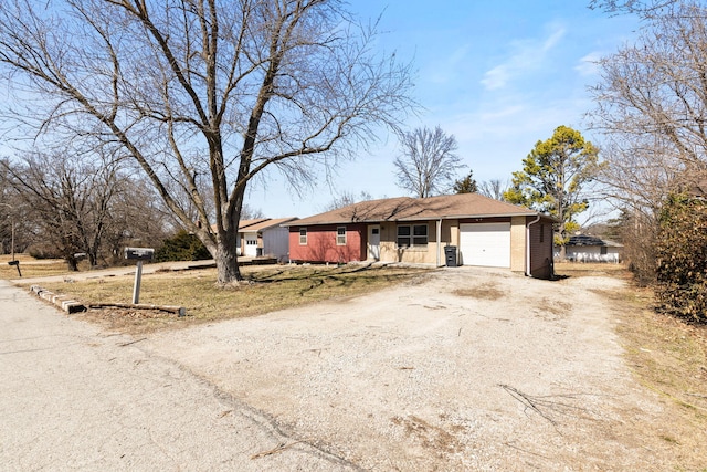 ranch-style house with a garage and dirt driveway