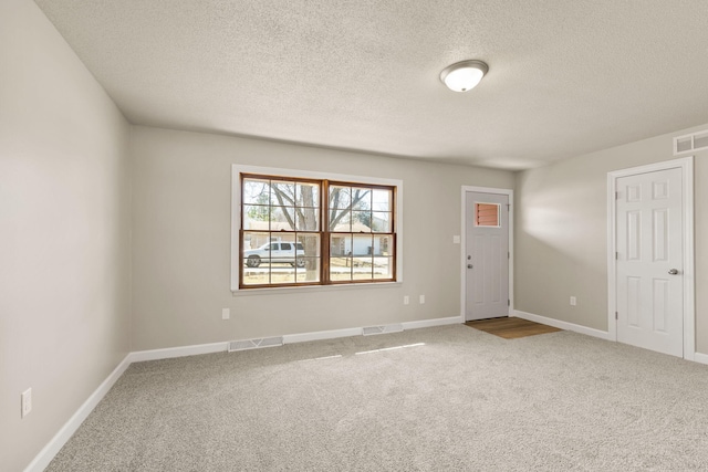 carpeted spare room featuring baseboards, visible vents, and a textured ceiling