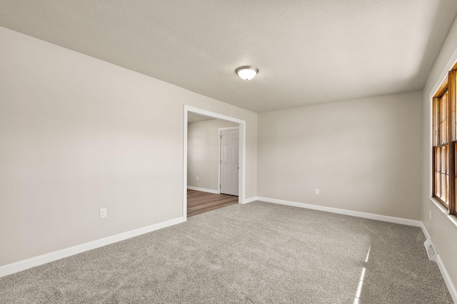 unfurnished room featuring carpet flooring, a textured ceiling, and baseboards