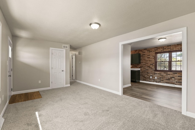 unfurnished living room with visible vents, carpet floors, a textured ceiling, and baseboards