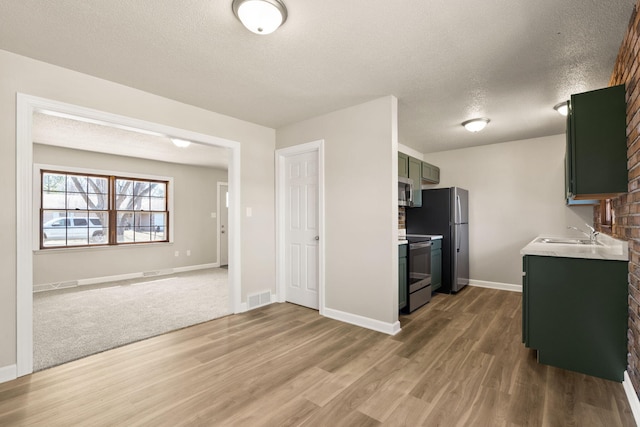 kitchen featuring light wood finished floors, visible vents, light countertops, appliances with stainless steel finishes, and a textured ceiling