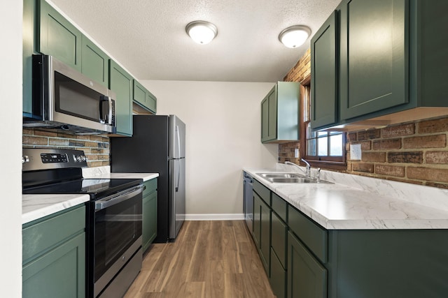 kitchen featuring a sink, appliances with stainless steel finishes, light countertops, green cabinetry, and decorative backsplash