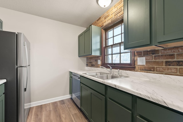 kitchen with a sink, stainless steel appliances, green cabinets, and light countertops