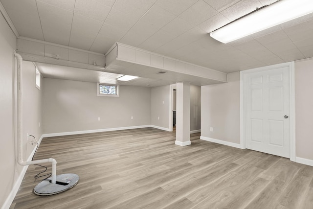 basement featuring visible vents, light wood-style floors, and baseboards