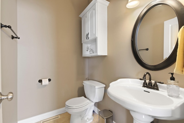 half bath with toilet, baseboards, visible vents, and a sink